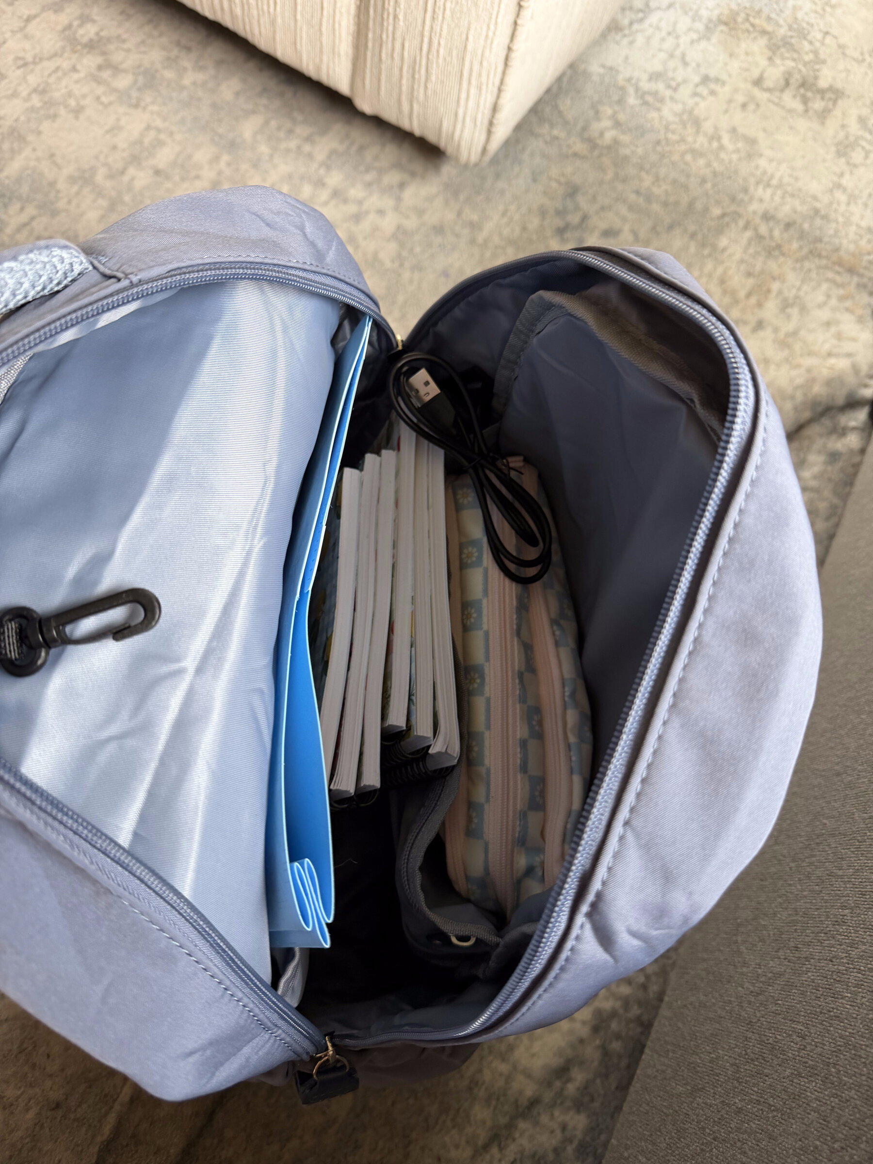 A packed backpack with folders, notebooks, and a pencil pouch inside, ready for the morning