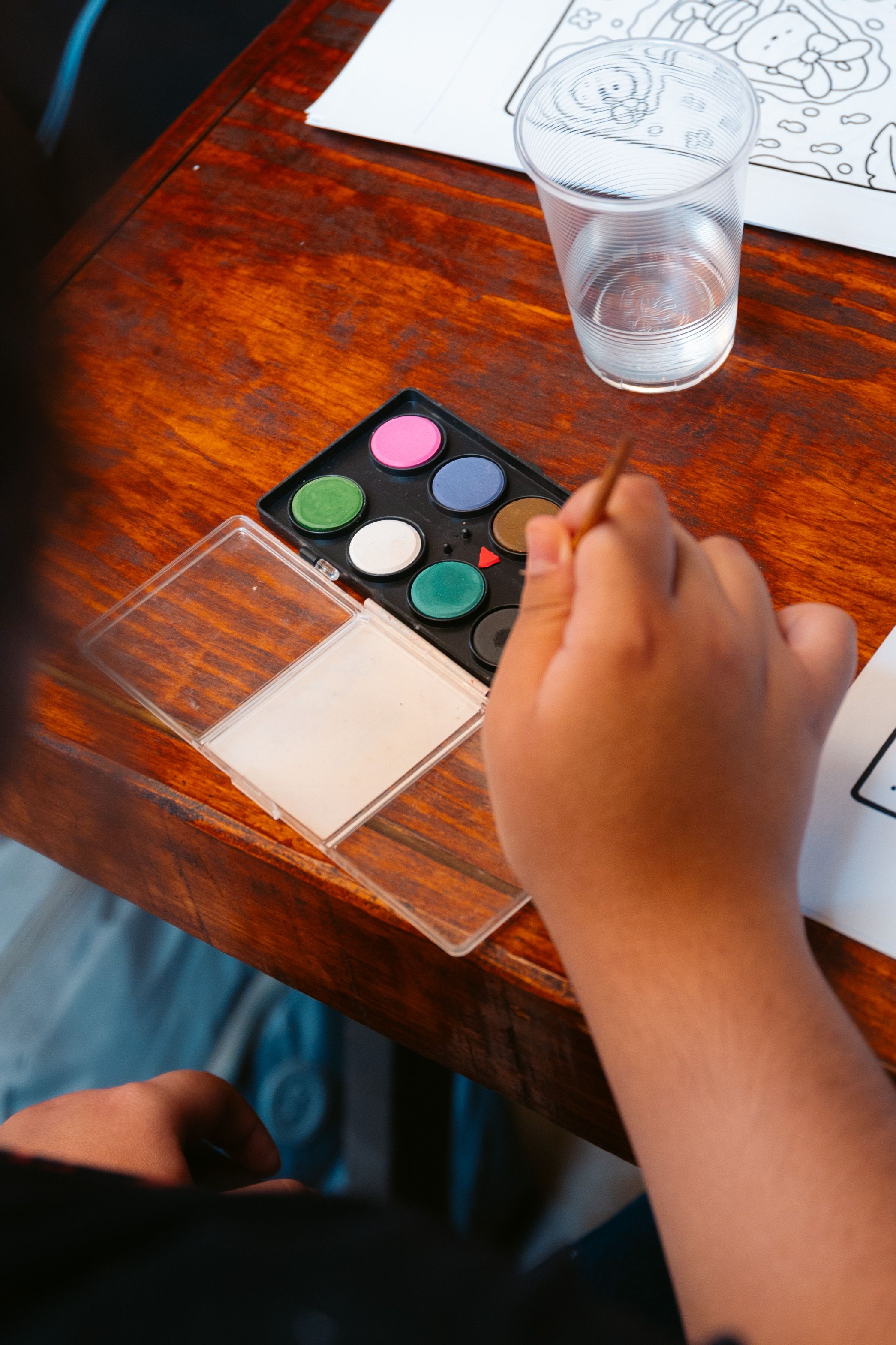 Child painting a watermelon shape with watercolors