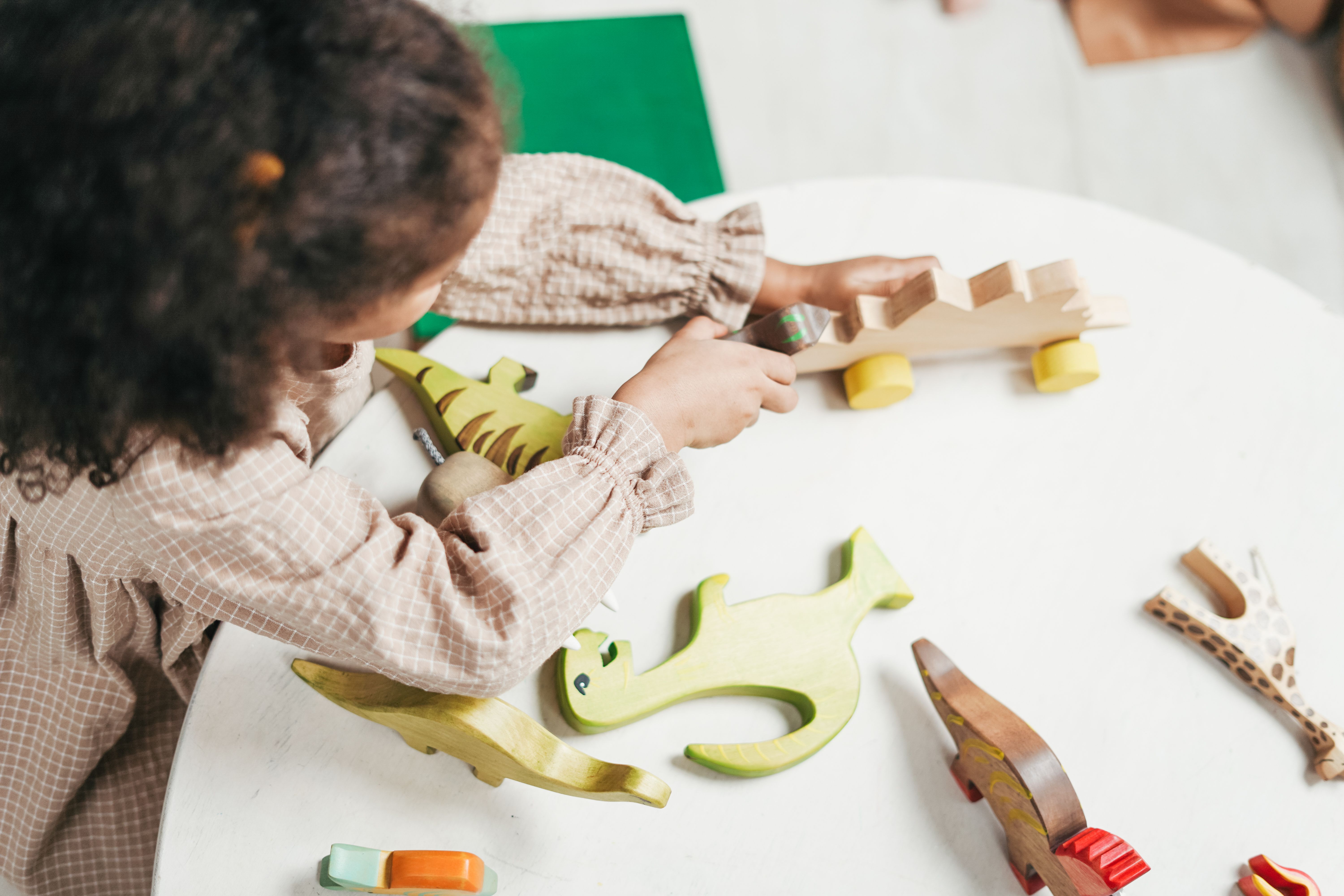 Toddler playing with wooden animal toys on a table