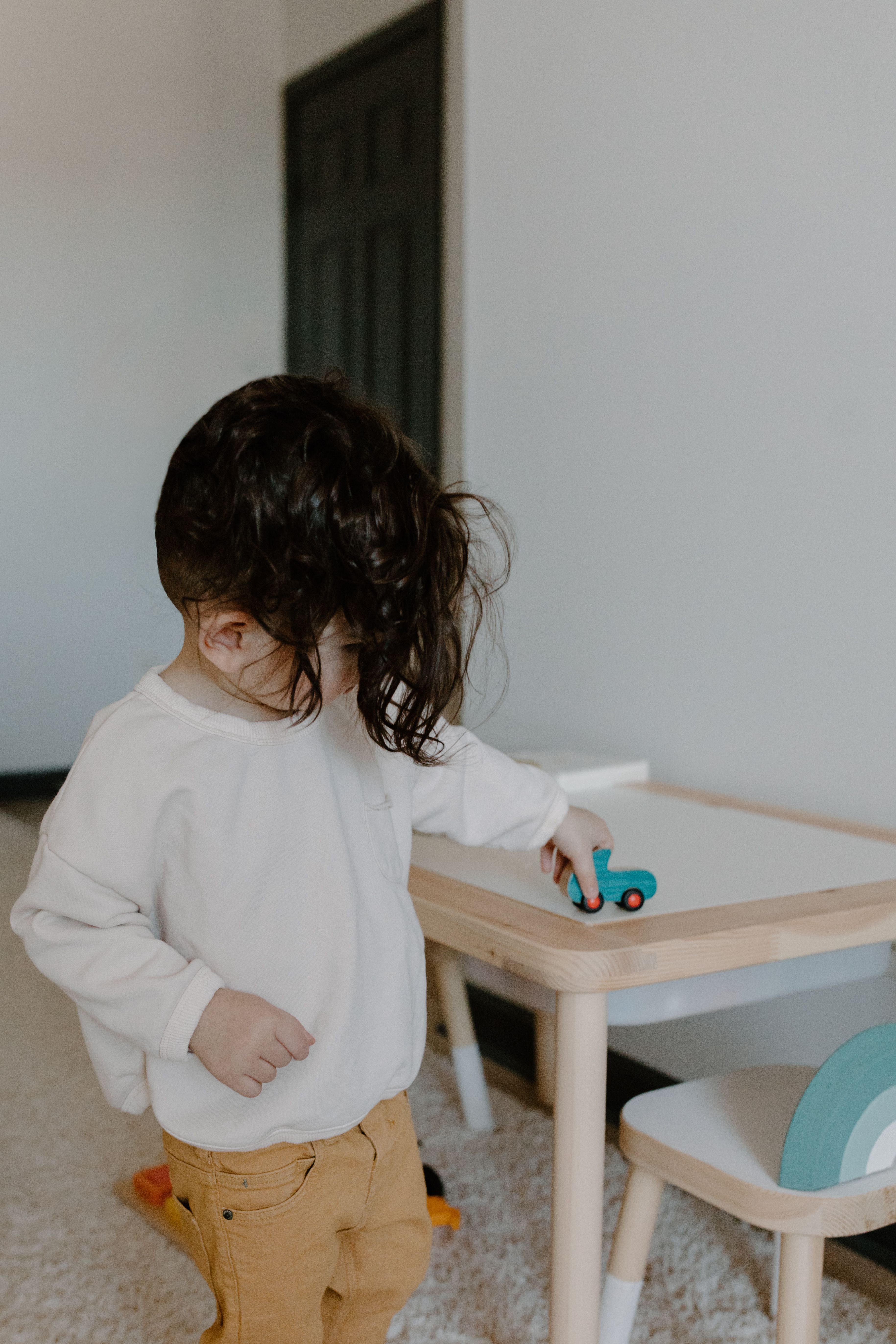 Toddler playing quietly alone with a toy car
