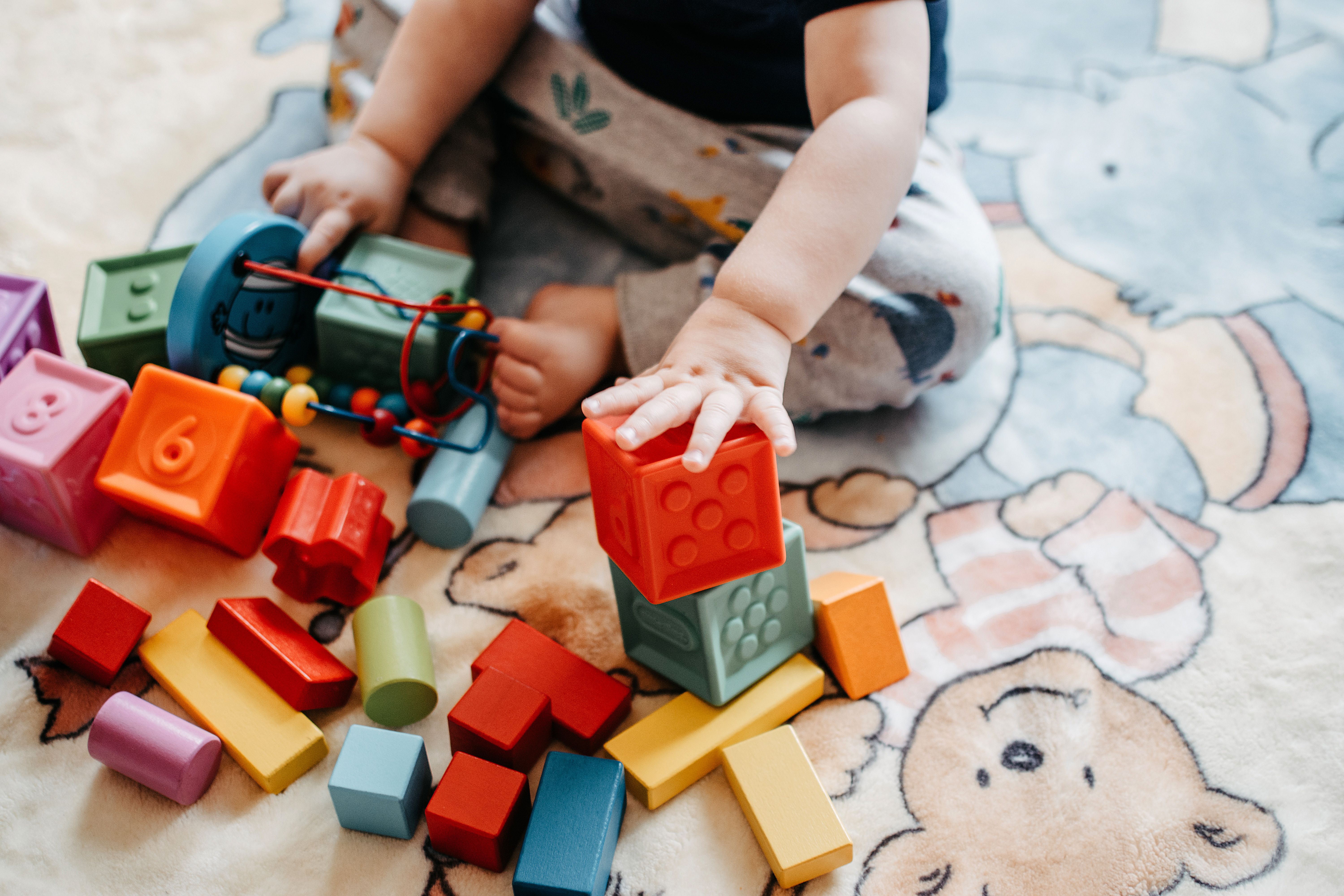 Toddler playing with colorful stacking blocks on the floor