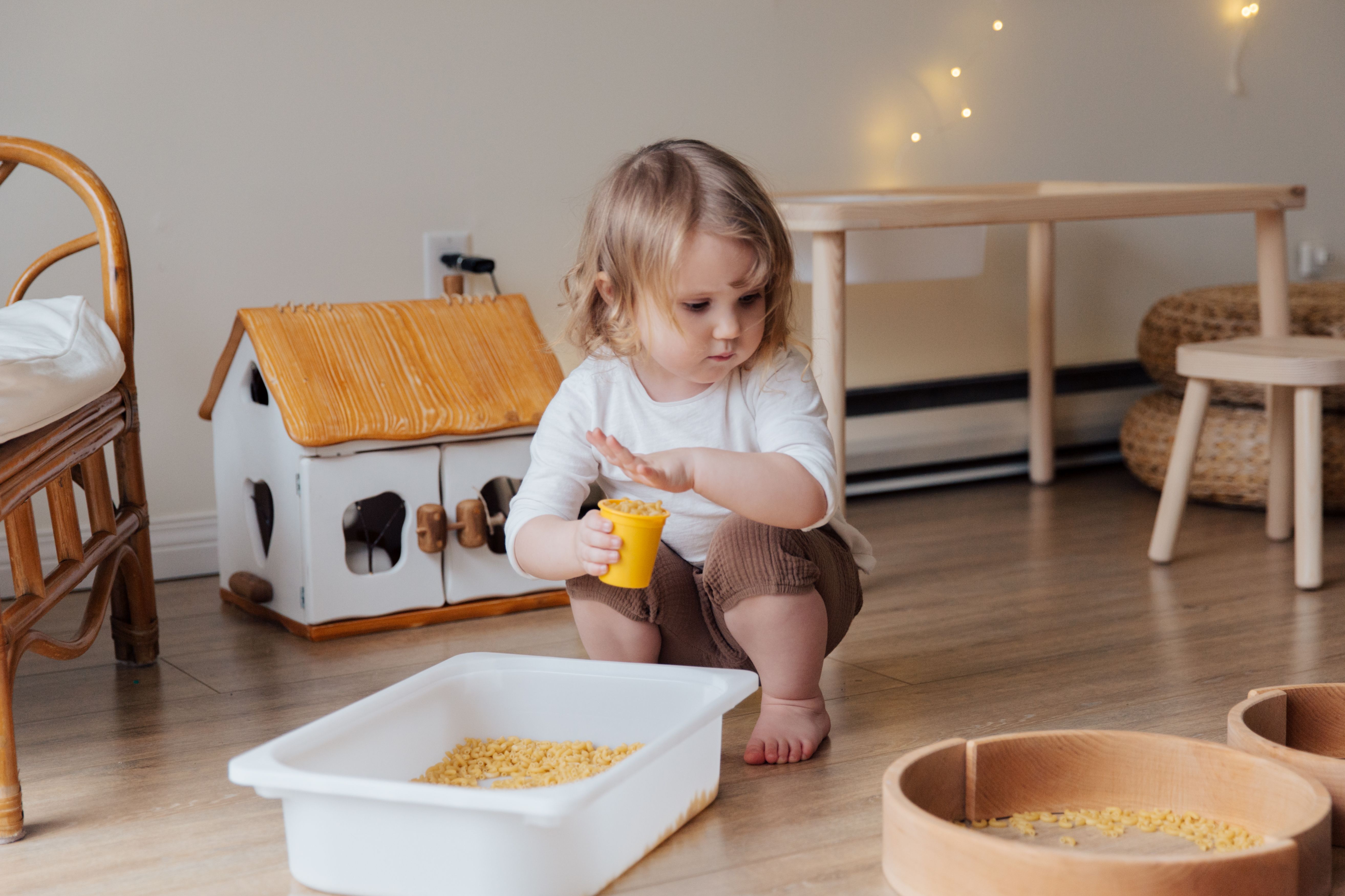 Child’s hand holding a yellow container filled with dry pasta